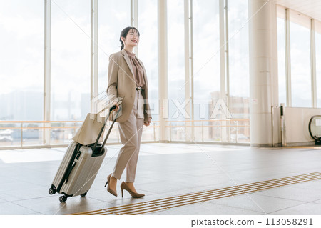 Businesswoman walking with a suitcase at the airport, station, building, public transport facility (overseas business trip, walking) Businesswoman walking with a suitcase at the airport, station, building, public transport facility (overseas business trip, walking) 113058291