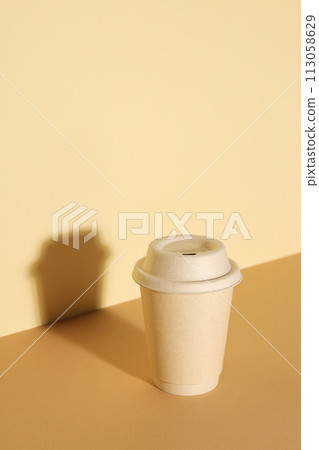 A paper cup with a lid on a light background A paper cup with a lid on a light background 113058629