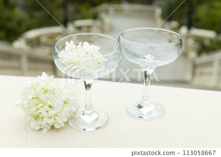 Two glass glasses with flowers on the background of the sea. 113058667