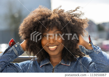 Joyful African American Woman with Lush Afro Hair Outdoors Joyful African American Woman with Lush Afro Hair Outdoors 113058867