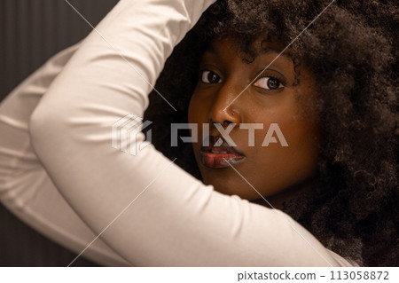 Close-up of a Pensive Black Woman with Afro Hair in a Casual White Top Close-up of a Pensive Black Woman with Afro Hair in a Casual White Top 113058872