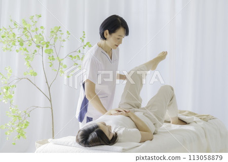 一位為年輕女性進行治療的中年女性脊椎按摩師 一位為年輕女性進行治療的中年女性脊椎按摩師 113058879