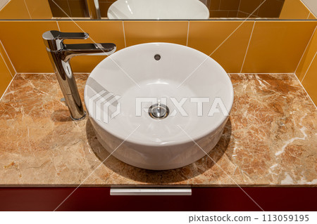 A Bathroom round white Sink With A Faucet And A Mirror 113059195