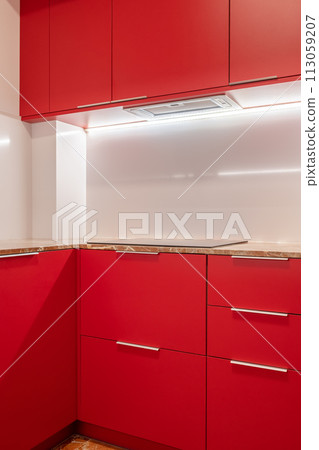 Minimalist kitchen corner with vibrant red cabinets and white walls Minimalist kitchen corner with vibrant red cabinets and white walls 113059207