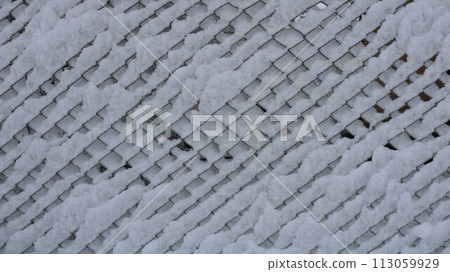 Snow sticking on a wire mesh fence, a fragment of fencing from a grate covered with a layer of wet fresh snow, a white texture graphic resource of winter with a geometric pattern Snow sticking on a wire mesh fence, a fragment of fencing from a grate covered with a layer of wet fresh snow, a white texture graphic resource of winter with a geometric pattern 113059929