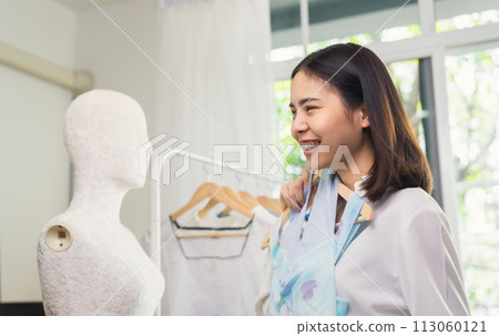 Beautiful Asian woman choose on clothing in a clothing store with mannequins. Beautiful Asian woman choose on clothing in a clothing store with mannequins. 113060121