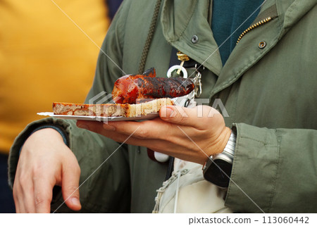 Customer holding bread with sausage at farmers market. Customer holding bread with sausage at farmers market. 113060442