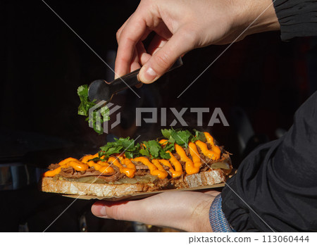 Customer holding bread with pulled meat at farmers market. Customer holding bread with pulled meat at farmers market. 113060444