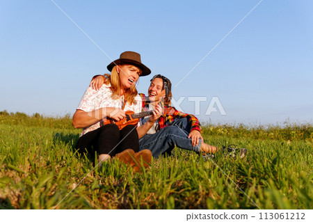 mother and daughter joyfully singing together while playing the ukulele on a sunny summer day, capturing the essence of family bonding and outdoor musical enjoyment 113061212