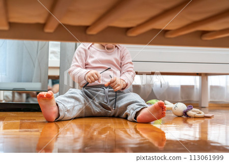 Baby with pacifier in mouth playing with sunglasses view from under crib Baby with pacifier in mouth playing with sunglasses view from under crib 113061999