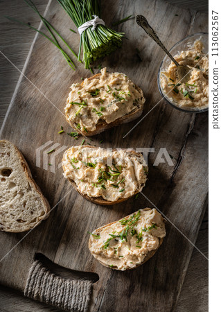 Close-up of bread slice with traditional Slovak bryndza spread made of sheep cheese with freshly cut chives placed on rustic wood 113062567
