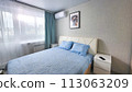 interior of the bedroom with a blue bedspread and pillows on the bed, a bedside table 113063209