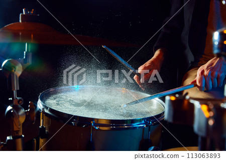 Close-up of drum with water drops jumping from stick's strike. Creative and impressive live performance Close-up of drum with water drops jumping from stick's strike. Creative and impressive live performance 113063893