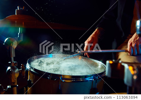 Close-up of drum with water drops jumping from stick's strike. Creative and impressive live performance Close-up of drum with water drops jumping from stick's strike. Creative and impressive live performance 113063894