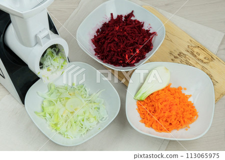 Onion, carrot and beet in a vegetable cutter on kitchen. Chopped carrot is falling into a bowl. Homemade healthy food. Health line. Onion, carrot and beet in a vegetable cutter on kitchen. Chopped carrot is falling into a bowl. Homemade healthy food. Health line. 113065975