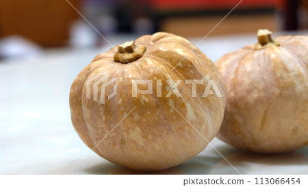 Two small pumpkins on table top. With blurred background. 113066454