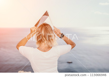 Digital nomad, Business woman working on laptop by the sea. Pretty lady typing on computer by the sea at sunset, makes a business transaction online from a distance. Freelance, remote work on vacation 113066946