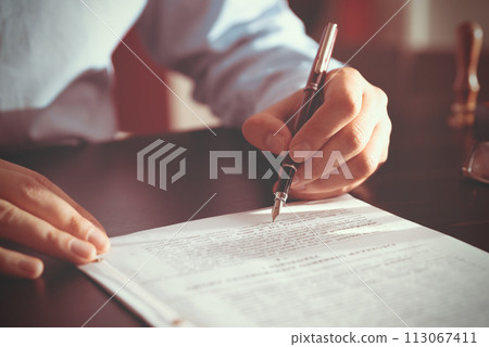 Notary public in office signing document Notary public in office signing document 113067411