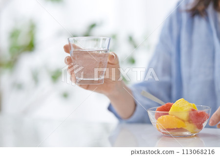 一名中年婦女的手拿著一杯水吃水果 一名中年婦女的手拿著一杯水吃水果 113068216