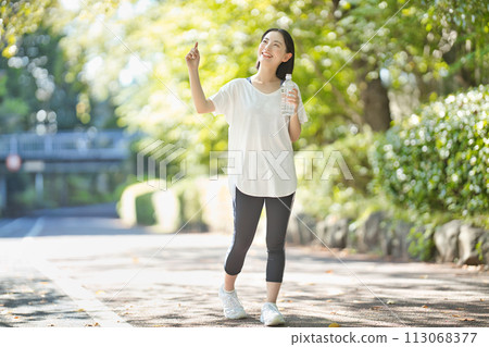 Young woman in sportswear drinking water from a plastic bottle 113068377