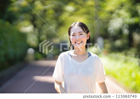 Smiling young woman running in sportswear 113068749