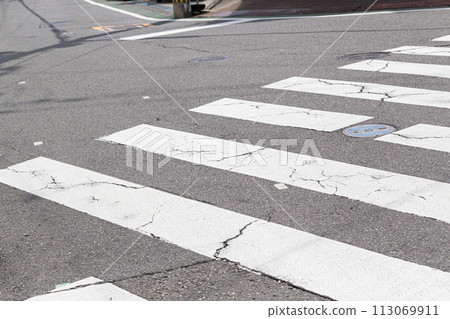 Crosswalk with cracks in the asphalt Crosswalk with cracks in the asphalt 113069911