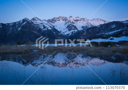 Sunset over the Pyrenees mountains with the reflection of the peaks in the water of the lake 113070370