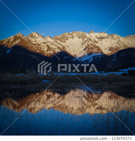Sunset over the Pyrenees mountains with the reflection of the peaks in the water of the lake Sunset over the Pyrenees mountains with the reflection of the peaks in the water of the lake 113070373