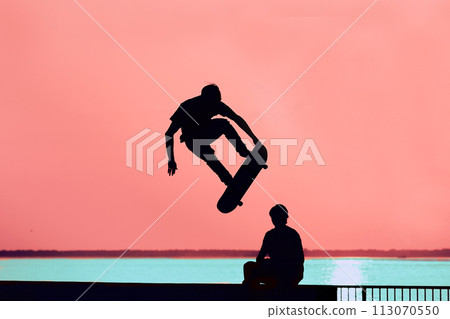 Unrecognizable teenage boy silhouette showing high jump tricks on scooter against 113070550