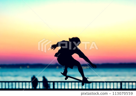 Unrecognizable teenage boy silhouette showing high jump tricks on scooter against Unrecognizable teenage boy silhouette showing high jump tricks on scooter against 113070559