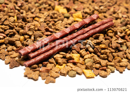 Treats for cats meat sticks sausages against the background of dry food. Complete diet for adult cats Treats for cats meat sticks sausages against the background of dry food. Complete diet for adult cats 113070821