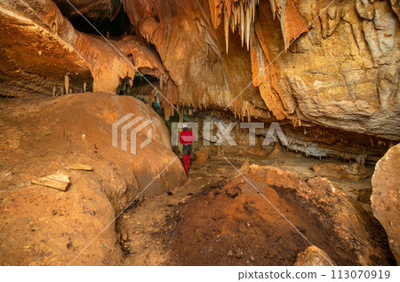 A speleologist with helmet and headlamp exploring a cave with rich stalactite and stalagmite A speleologist with helmet and headlamp exploring a cave with rich stalactite and stalagmite 113070919