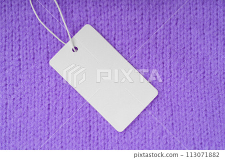 Template of blank clothing label, price tag on purple knitted sweater background 113071882
