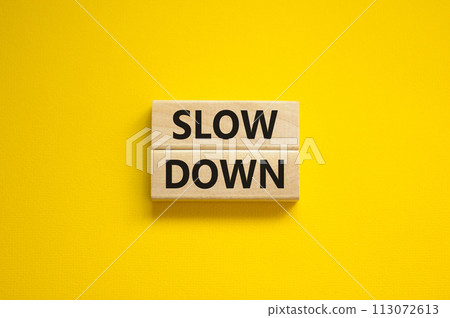 Time to slow down symbol. Concept words Slow down on wooden blocks on a beautiful yellow background. Business and slow down concept. Copy space. Time to slow down symbol. Concept words Slow down on wooden blocks on a beautiful yellow background. Business and slow down concept. Copy space. 113072613
