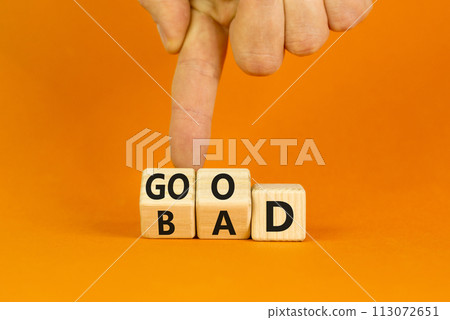 Good or bad symbol. Turned wooden cubes and changed the word bad to good. Beautiful orange table, orange background, copy space. Businessman hand. Business and bad or good concept. 113072651
