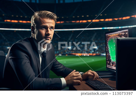 a sports commentator sits at the monitor against the backdrop of the football field of the stadium 113073397
