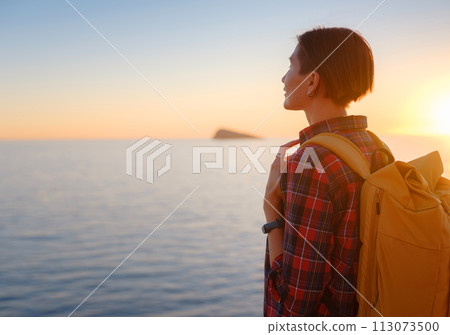 Young woman hiking on rocky beach in Spain, Benidorm. Watching the choppy sea and the bay. traveler enjoying freedom in serene nature landscape 113073500