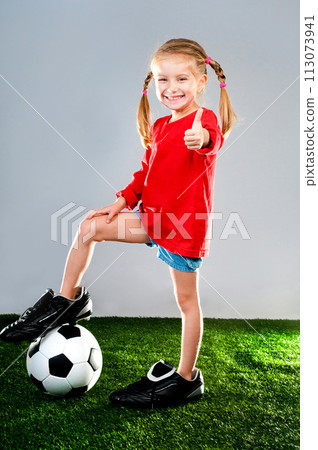 little girl with soccer ball in boots on a green lawn 113073941