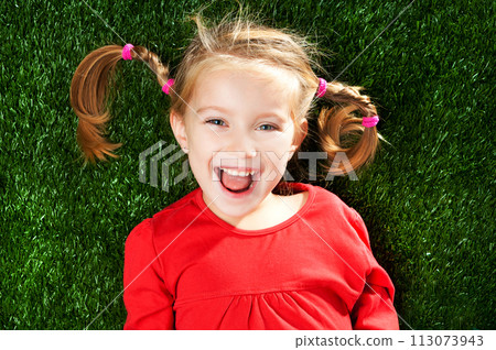 little girl smiling on a green lawn 113073943
