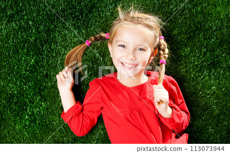 little girl smiling on a green lawn 113073944