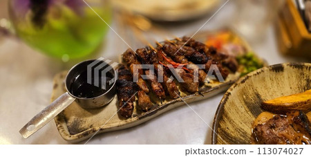 Homemade beef Satay marinated with spice and sweet soy sauce, coriander beef satay, served on plate with onion, chilli, soy sauce and tomato Homemade beef Satay marinated with spice and sweet soy sauce, coriander beef satay, served on plate with onion, chilli, soy sauce and tomato 113074027