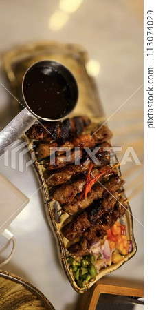 Homemade beef Satay marinated with spice and sweet soy sauce, coriander beef satay, served on plate with onion, chilli, soy sauce and tomato Homemade beef Satay marinated with spice and sweet soy sauce, coriander beef satay, served on plate with onion, chilli, soy sauce and tomato 113074029