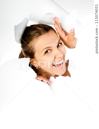 young girl looking through hole in white paper young girl looking through hole in white paper 113074051