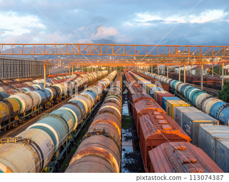 Tanks with fuel on the railway tracks at sunset. Sunset at the train station. The cargo part of the station. industrial zone against the backdrop of mountains. Fuel wagons. Cargo transportation Tanks with fuel on the railway tracks at sunset. Sunset at the train station. The cargo part of the station. industrial zone against the backdrop of mountains. Fuel wagons. Cargo transportation 113074387
