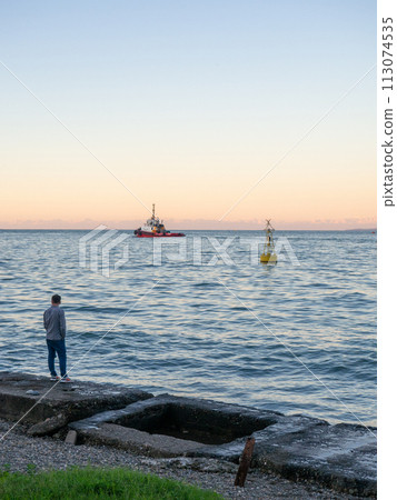 Port area. Tugboat on the road. A buoy in the bay of the port. Marine urban landscape. Port area. Tugboat on the road. A buoy in the bay of the port. Marine urban landscape. 113074535