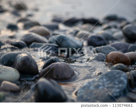 Pebbles on the seashore close-up. Rocky beach. Stones close-up with bokeh. Gray natural background. The concept of rest on the seashore. Autumn on the seashore. Waves and wet pebbles Pebbles on the seashore close-up. Rocky beach. Stones close-up with bokeh. Gray natural background. The concept of rest on the seashore. Autumn on the seashore. Waves and wet pebbles 113074661