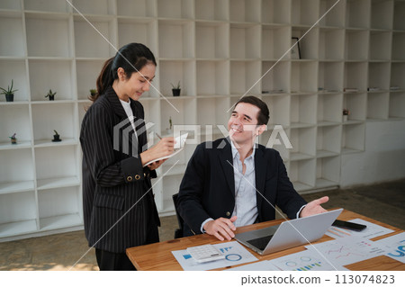 Company CEO and Top Manager Talking, Using Laptop Computer in office. Two Successful Professional People Brainstorm, Find Solution to Their e-Commerce Software Investment Strategy Company CEO and Top Manager Talking, Using Laptop Computer in office. Two Successful Professional People Brainstorm, Find Solution to Their e-Commerce Software Investment Strategy 113074823