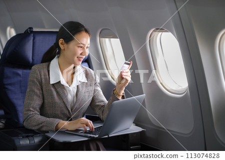 Asian female using laptop computer and holding credit card in airplane, Business traveling and technology concept. Asian female using laptop computer and holding credit card in airplane, Business traveling and technology concept. 113074828