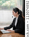 Beautiful Asian call center operator talking with customer using laptop . 113074892