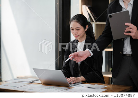 Company CEO and Top Manager Talking, Using Laptop Computer in office. Two Successful Professional People Brainstorm, Find Solution to Their e-Commerce Software Investment Strategy 113074897